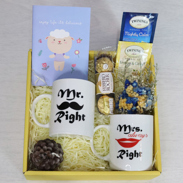 A gift set box for married couples with his and hers comical mugs, tea bags, chocolates, flowers, a candle, notebook and custom message card.	