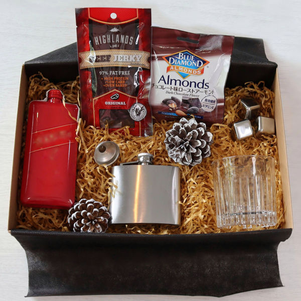 A Johnnie Walker Red Label gift box with metal ice cubes, a hip flask, a drinking glass and snacks